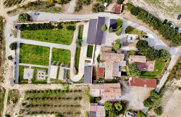 Vista aerea zenitale dall'alto dell'intera tenuta Hortus con fabbricati, giardini geometrici, viali in ghiaia e uliveti confinanti.